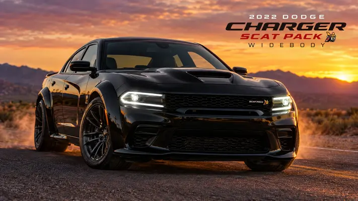 2022 Dodge Charger Scat Pack Widebody in black parked on desert highway at sunset with glowing LED headlights